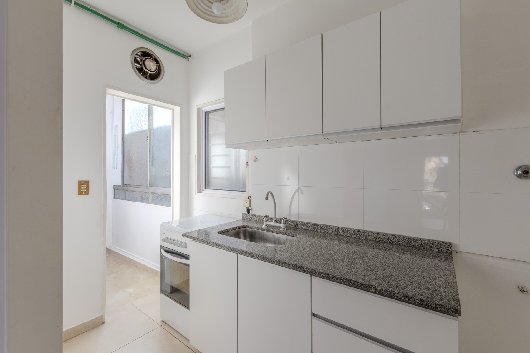 Cocina equipada con bacha, mesada de granito y alacenas blancas